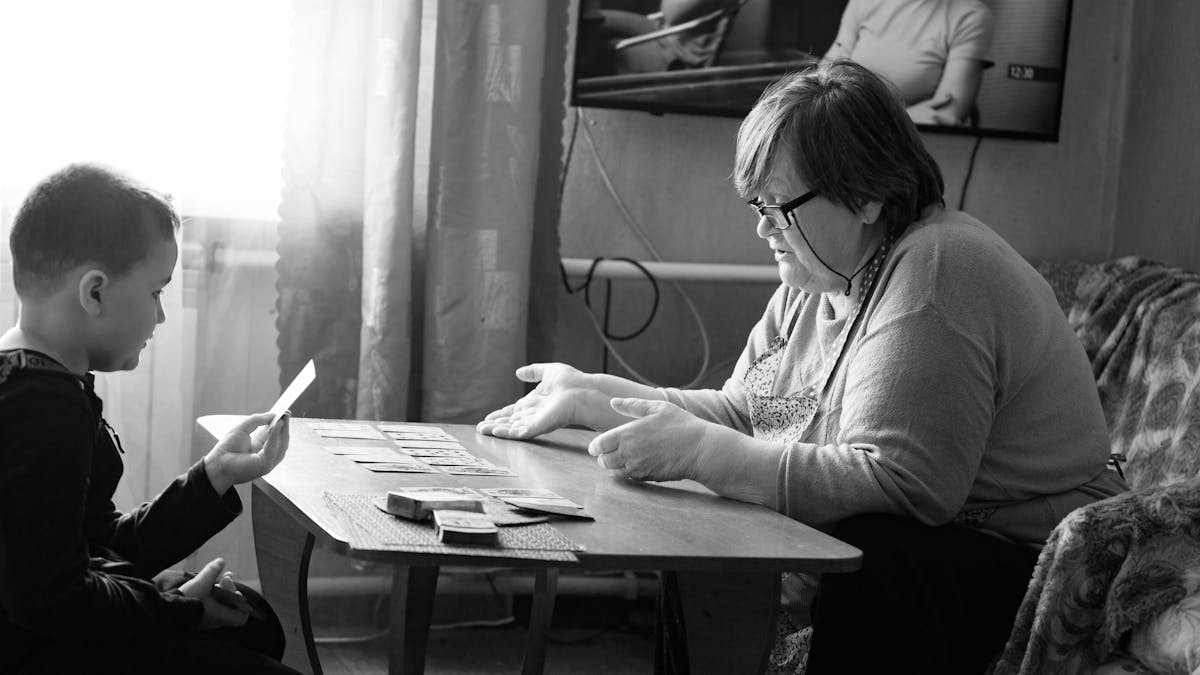 Heartwarming black and white scene of a grandmother and grandson playing cards indoors.